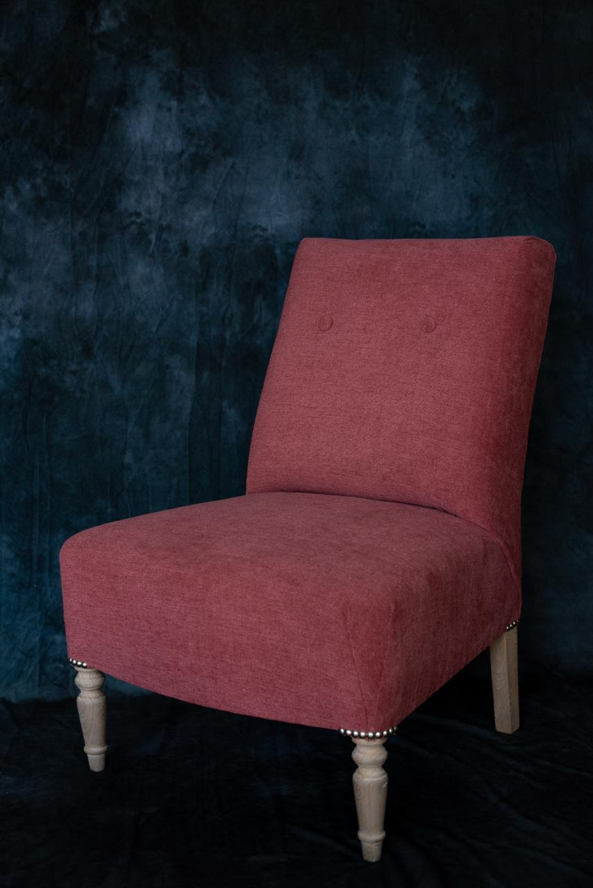 chaufeuse recouverte d'un tissu vieux rose avec deux boutons sur le dossier